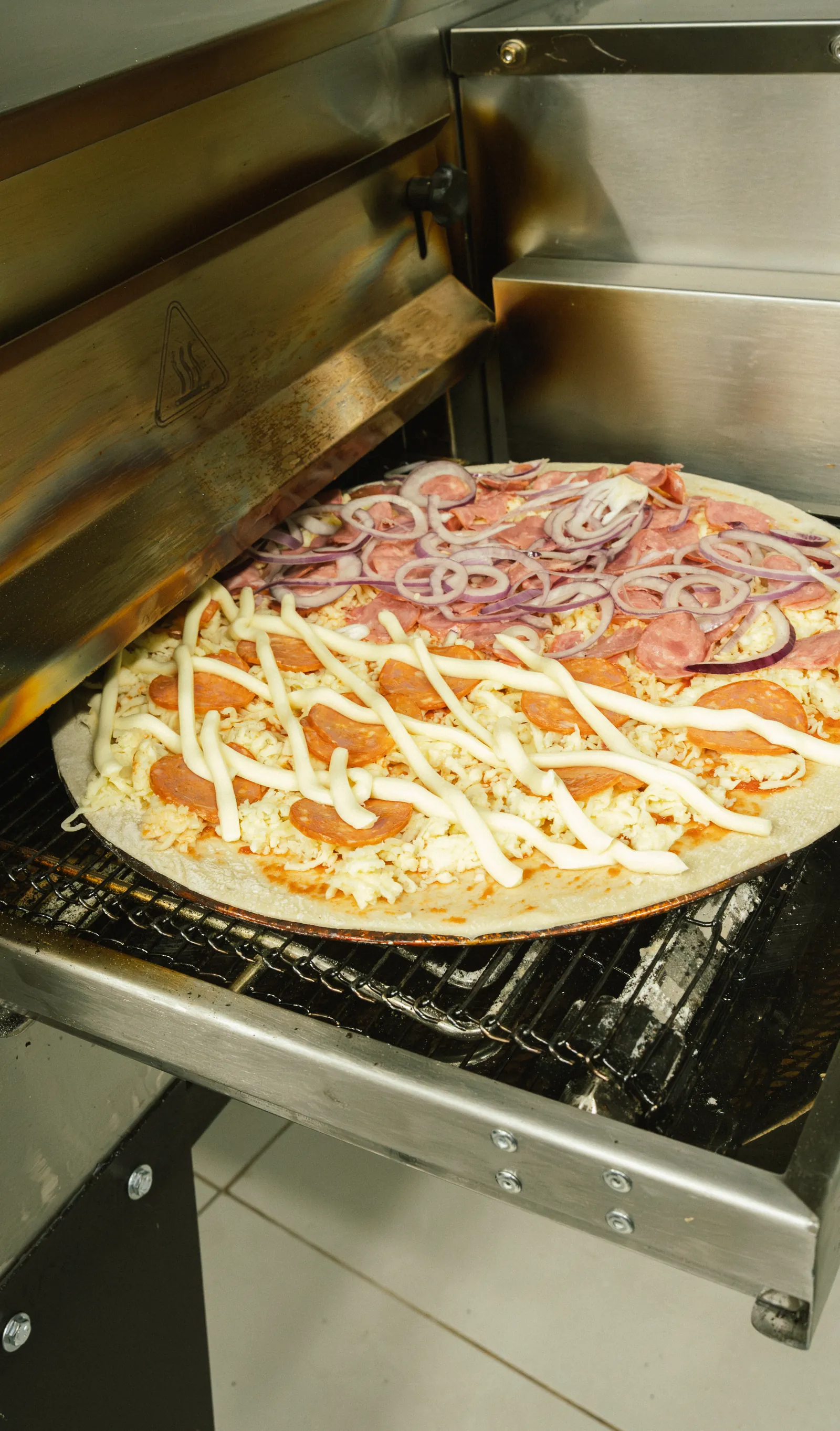 Pizza entrando no forno de esteira da unidade