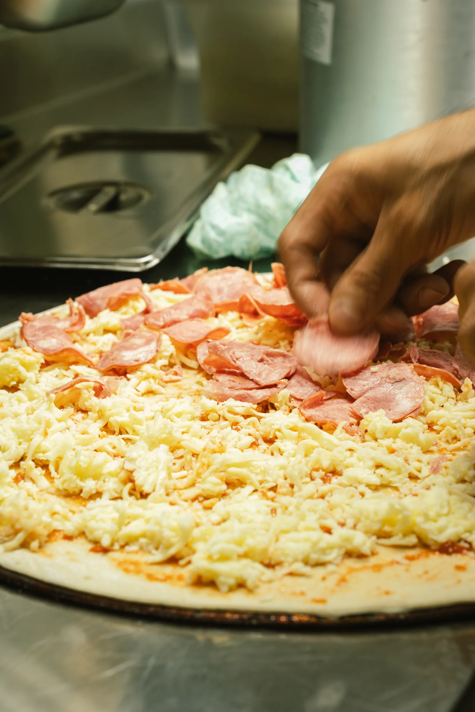 Cozinheiro montando a cobertura de uma pizza na bancada